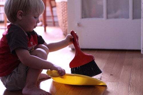 Bambino che spazza il pavimento come parte delle sue faccende quotidiane.