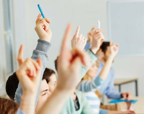 Bambini che alzano la mano a scuola.