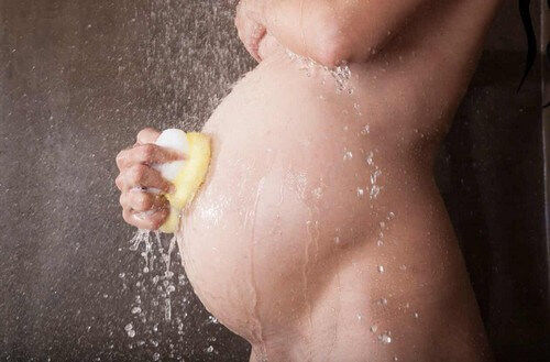 Donna in gravidanza fa la doccia.